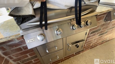 A close-up of a stainless steel grill with a black handle and a logo that reads "R5".