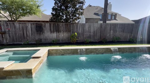 A pool with a waterfall and a wooden fence.