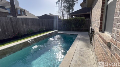 A small pool in a backyard with a brick wall and a bicycle leaning against it.