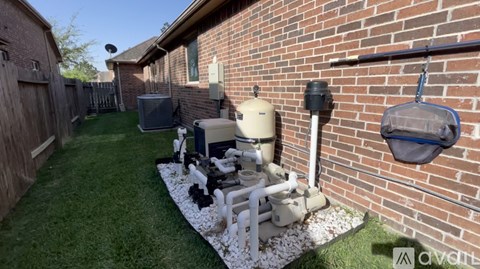 A backyard with a lawn and a wall with pipes.