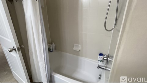A white bathtub with a shower head and a white door.