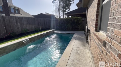 A small residential pool with a brick wall and a bicycle leaning against it.