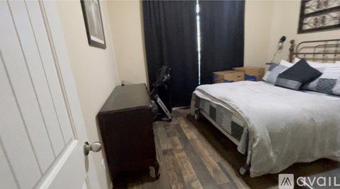 A bedroom with a bed, nightstand, and a window with curtains.