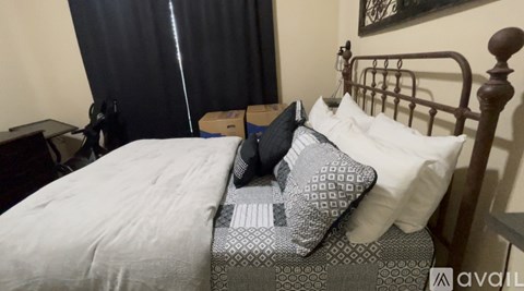 A bed with a white sheet and a grey pillow is in the image.