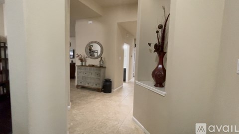A hallway with a round mirror and a vase on the wall.