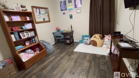 A room with a bookshelf, a bean bag chair, and a desk with a computer.