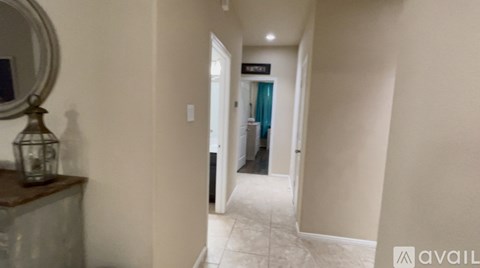 A hallway with a mirror on a dresser and a door at the end.