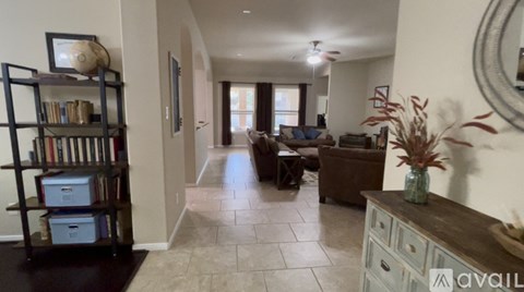 A living room with a couch, a coffee table, a bookshelf, and a vase on a side table.