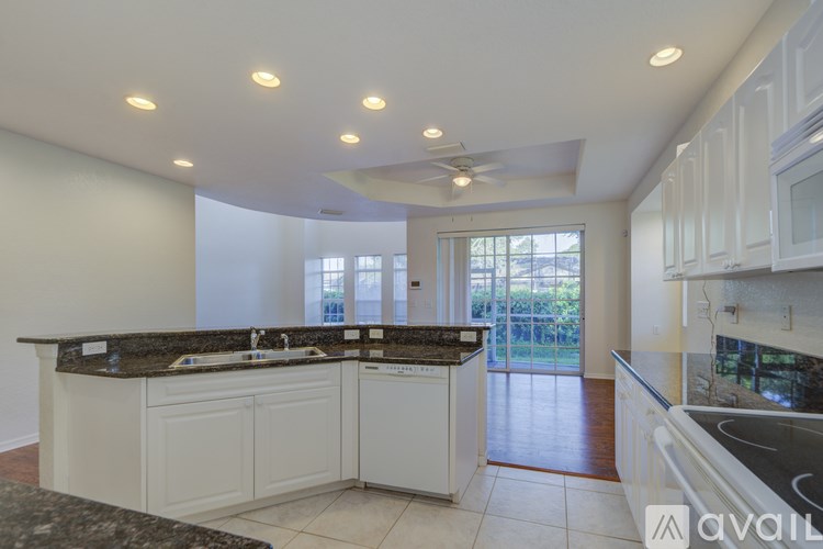 A kitchen with white cabinets and a black counter top.