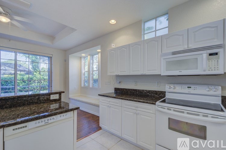 A kitchen with white cabinets and a black countertop.