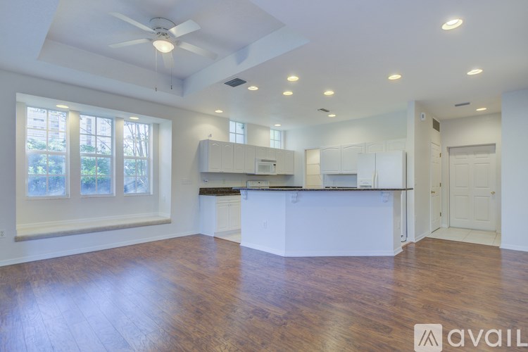 A spacious kitchen and living room with hardwood floors and a ceiling fan.