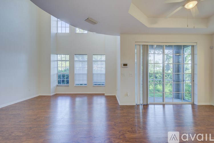 A spacious room with wooden floors and a sliding glass door leading to a balcony.