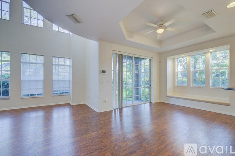 A spacious room with wooden floors and large windows.