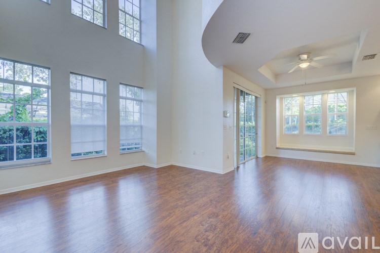 A spacious room with wooden floors and large windows.