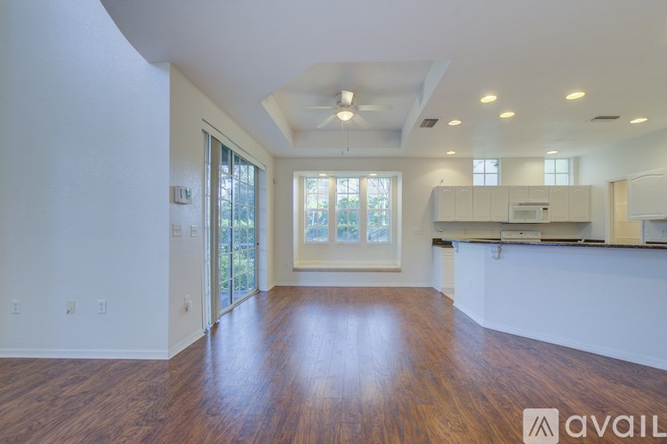 A spacious living room with hardwood floors and a kitchen area in the background.