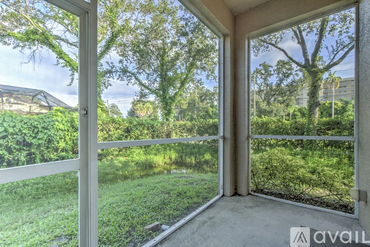 A balcony with a view of a green lawn and trees.