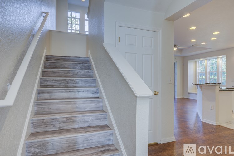 A staircase with wooden steps and white railings leads to a bright room.