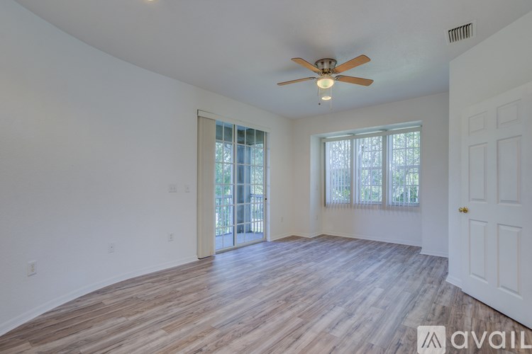 A room with a ceiling fan and sliding glass doors.