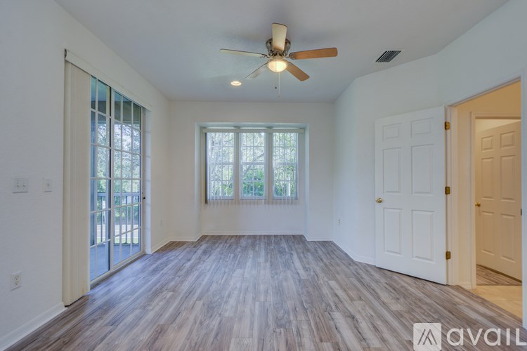A spacious room with a ceiling fan and sliding glass doors leading to a balcony.