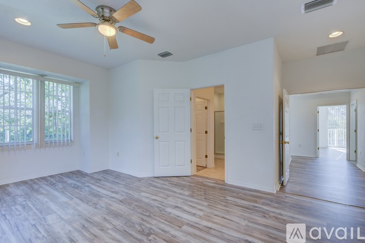 A spacious room with a ceiling fan and wooden flooring.