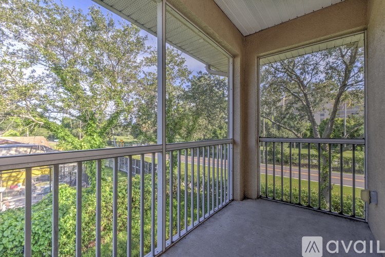 A balcony with a metal railing and a view of a street and trees.