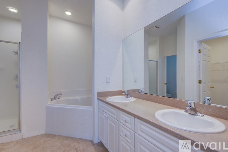 A bathroom with a large mirror, a sink, and a bathtub.