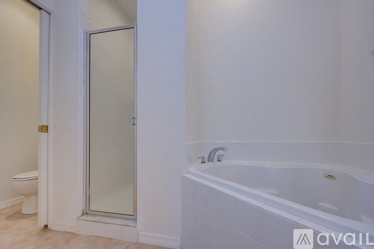 A bathroom with a white tub and a glass shower door.
