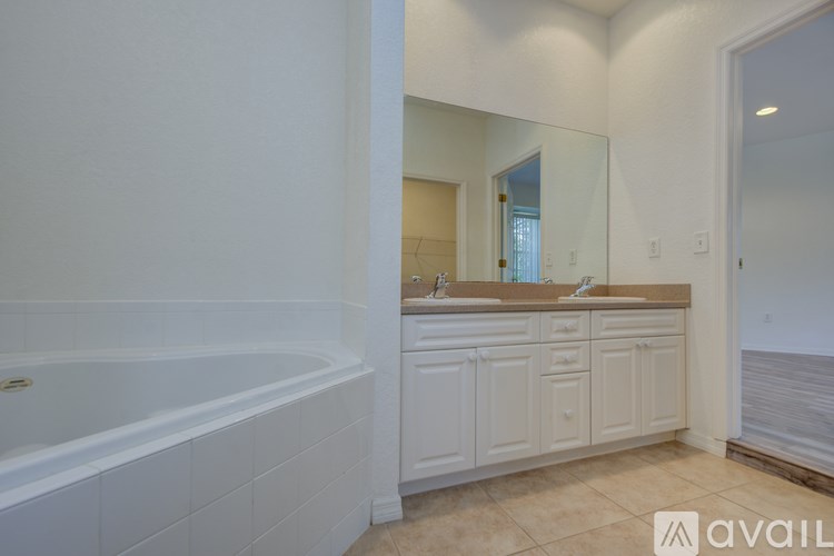 A bathroom with a tub, sink, and mirror.
