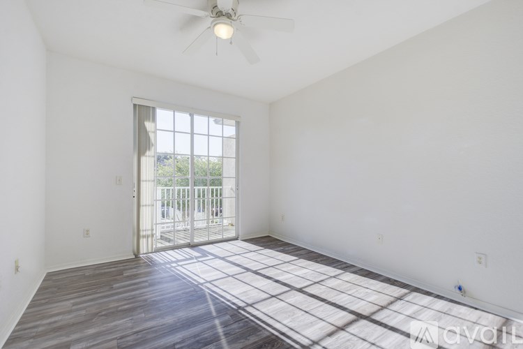 A room with a ceiling fan and a sliding glass door leading to a balcony.