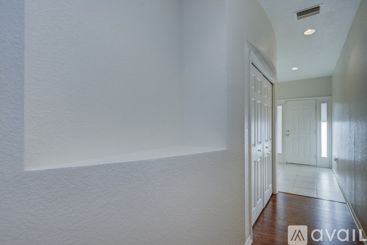 A hallway with white walls and a wooden floor.