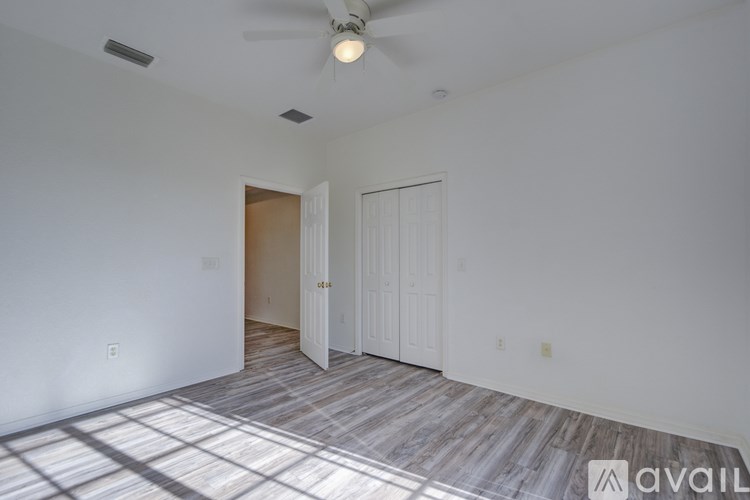 A room with a ceiling fan and a door leading to another room.