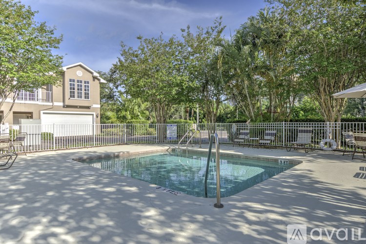 A pool surrounded by trees and a house in the background.