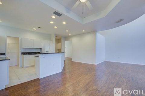 A spacious kitchen with white cabinets and a wooden floor.