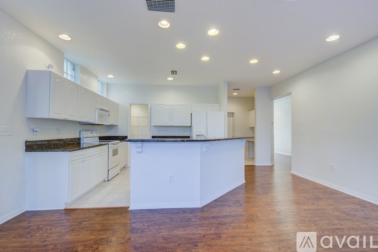A spacious kitchen with white cabinets and a wooden floor.