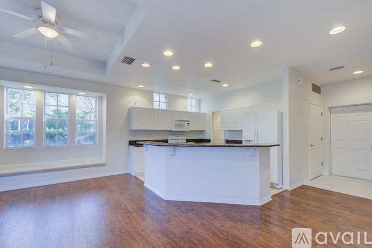 A spacious kitchen with white cabinets and a wooden floor.