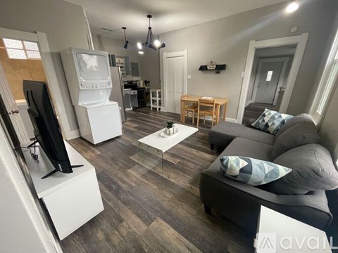 A living room with a grey couch and a television on a stand.