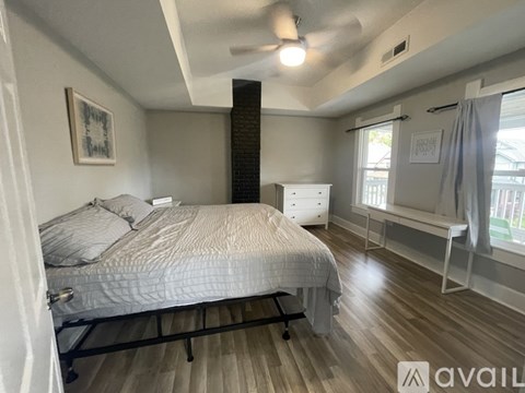 A bedroom with a bed, dresser, and window.