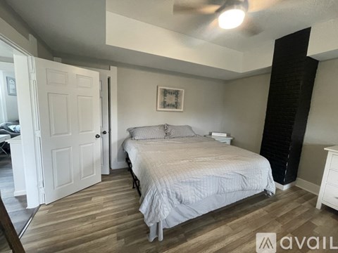 A bedroom with a bed, dresser, and a door leading to a balcony.