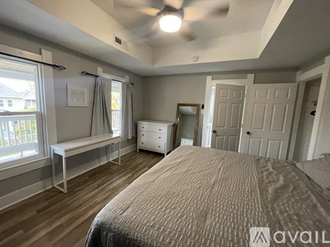A bedroom with a large bed, a window with a bench, and a dresser.