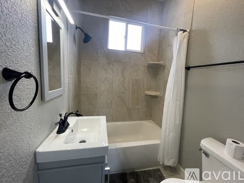 A bathroom with a white sink, bathtub, and toiletries.