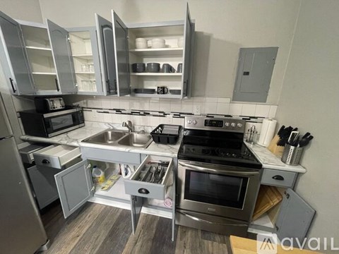 A kitchen with a stove, sink, and cabinets.