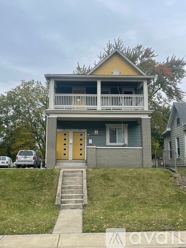A two-story house with a yellow door and a balcony.