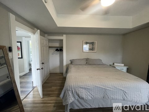 A bedroom with a bed, nightstand, and a painting on the wall.