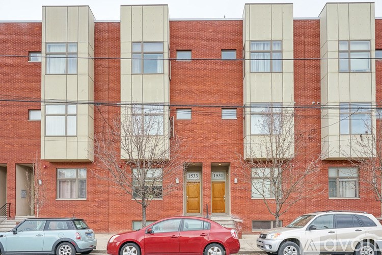 A red car is parked in front of a building with a beige facade.