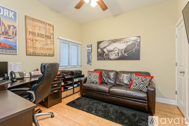 A living room with a brown leather couch and a poster of a vintage car.