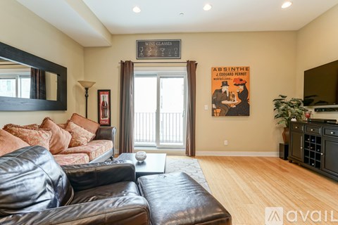 A living room with a leather couch and a poster on the wall.
