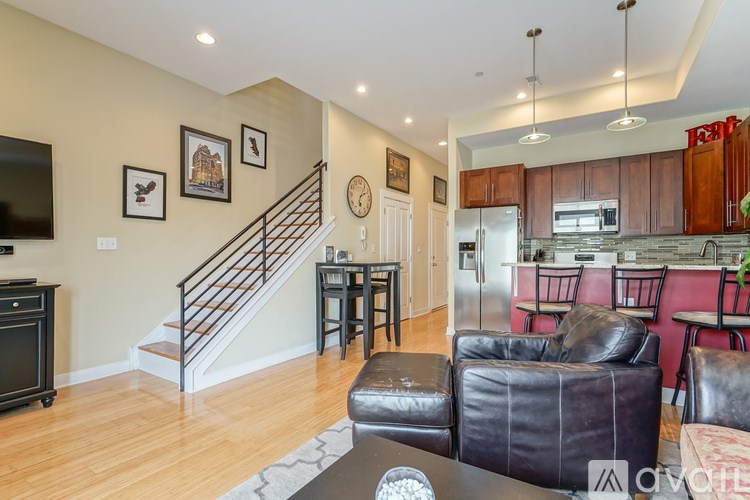 A living room with a staircase and a kitchen area in the background.