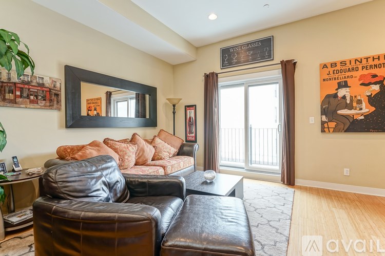 A living room with a black leather couch and a framed poster on the wall.