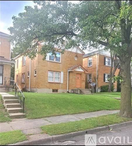A tree is in front of a brick house.