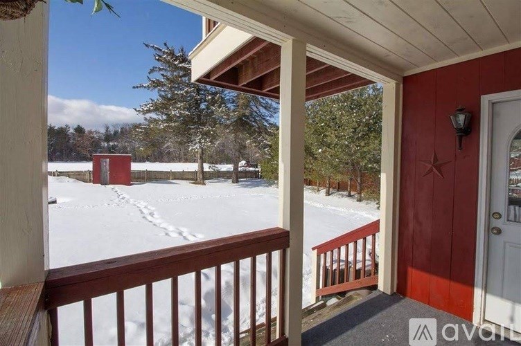 A porch with a red door and a snowy landscape in the background.